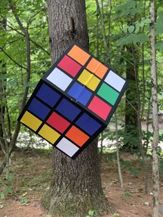 a rubik cube hanging from a tree in the woods