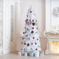 a white christmas tree decorated with red and silver baubs, ornaments and presents