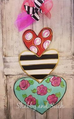 two hearts are hanging on a door with pink and black flowers in the center, one is