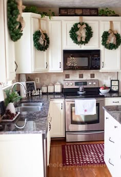 a kitchen decorated for christmas with wreaths on the oven and dishwasher above