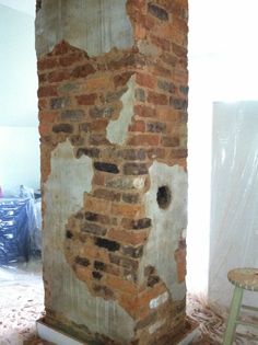 an old brick pillar in the middle of a room under construction with a ladder nearby