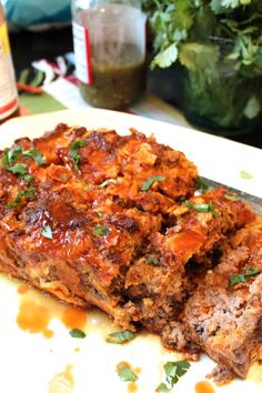 two meatloafs sitting on top of a white plate next to a green plant