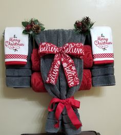 christmas themed towels hanging on the wall with red bows and pineconis attached to them