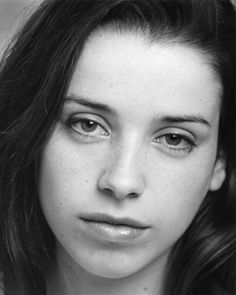 a black and white photo of a woman with freckles on her face looking at the camera