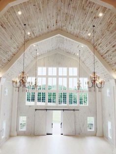 a large open room with chandeliers and windows in the ceiling is decorated with wood planks