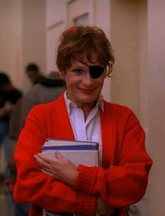 a woman with eye patches on her face is holding a binder and smiling at the camera