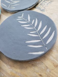 two blue plates with white leaves on them sitting on a table next to some scissors