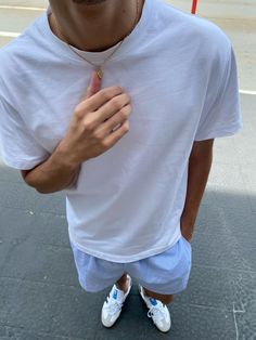 a man in white shirt and blue shorts standing next to street with red umbrella over his head