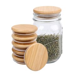 a jar filled with lots of green beans next to a stack of wooden lids on top of each other