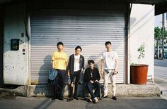 three men standing next to each other in front of a garage