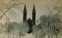 a black and white photo of a snowy path leading to an old building with two towers