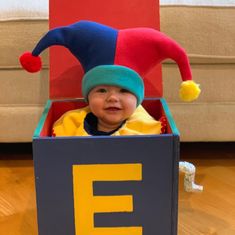 a small child in a box with a clown hat on his head and the letter e inside it