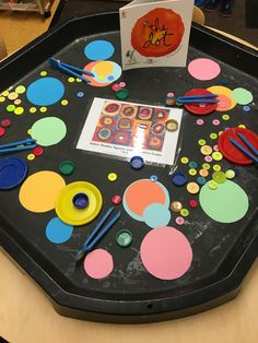 an art table with lots of different colored circles and paintbrushes on the tray