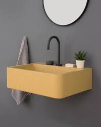 a bathroom sink sitting under a mirror next to a potted plant