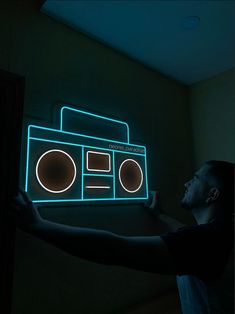 a man is holding up a neon sign with a radio on it's side