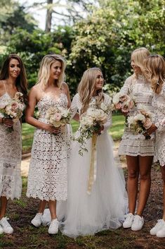 a group of women standing next to each other wearing dresses and holding bouquets in their hands