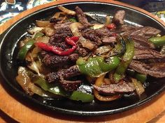 steak and peppers in a skillet on a table