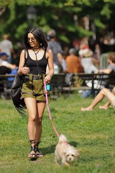 a woman walking her dog on a leash in the park while people sit and watch