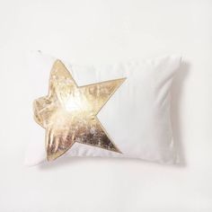 a white pillow with a gold star on the front and back, against a white background