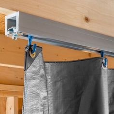 a metal curtain is hanging on the side of a wooden structure with blue handles and hooks