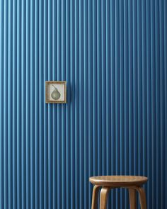 a wooden stool sitting in front of a blue wall