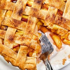 an apple pie on a white plate with a fork and serving utensil next to it