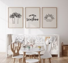 a white crib with three pictures hanging on the wall and two chairs in front of it