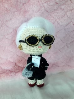 a crocheted doll with sunglasses and a name tag on it's chest