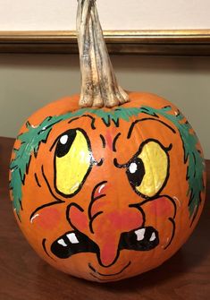 a painted pumpkin sitting on top of a wooden table