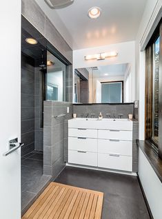 a bathroom with a shower, sink and mirror next to a door that leads to another room