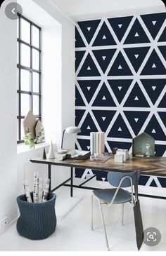 a room with a desk, chair and wallpaper in the shape of triangles