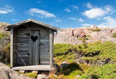 an outhouse on the side of a mountain with a heart hanging from it's door