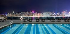 an empty swimming pool in front of a large cityscape with skyscrapers at night