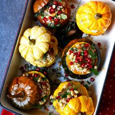 pumpkins and gourds are arranged on a platter with pomegranates