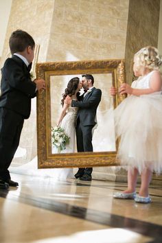 a man and woman are taking a photo in front of a mirror with their wedding pictures