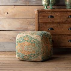 an ottoman sitting on top of a wooden floor next to a dresser and vases