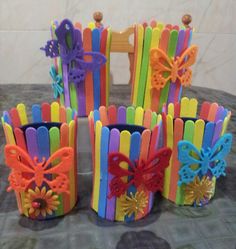 there are many different colored toothbrush holders on the table with flowers and butterflies in them