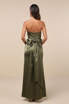 the back of a woman wearing a green dress with a large bow at the waist