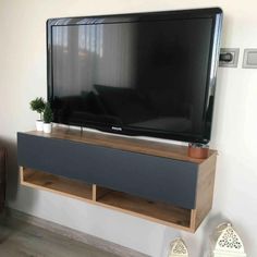 a flat screen tv sitting on top of a wooden shelf