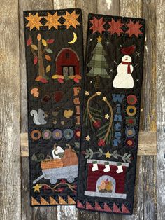 two quilted wall hangings decorated with christmas scenes and snowmen on black fabric