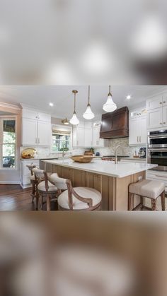 a large kitchen with white cabinets and wooden floors