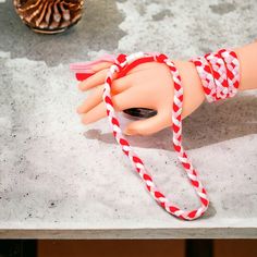 a doll's hand with red and white bracelets on top of a table