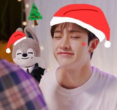 a young man wearing a santa hat and holding a stuffed animal in front of him