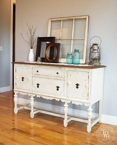 an old white dresser with two vases and a mirror on it's top