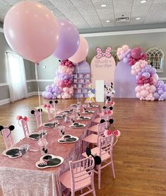 a table set up for a minnie mouse birthday party with pink and purple balloon decorations