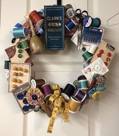 a wreath made out of sewing supplies and thread on the front door with a book