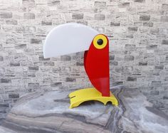 a red and yellow bird with a white disc on it's head sitting on top of a rock