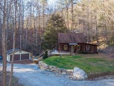 a small cabin in the woods with a driveway leading to it and a car parked on the side