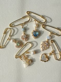 several different types of brooches and ear clips on a white surface with one being held by a pair of scissors