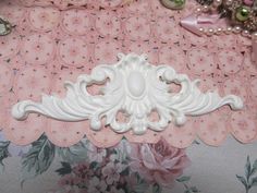 a close up of a decorative object on a pink table cloth with flowers and pearls